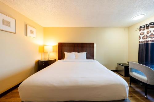 a bedroom with a large white bed and a chair at King City Motel by OYO Pasco in Pasco