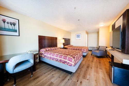 a hotel room with two beds and a flat screen tv at King City Motel by OYO Pasco in Pasco