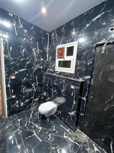 a black marble bathroom with a toilet and a microwave at Grand Luxury Apartments - Downtown Cairo in Cairo