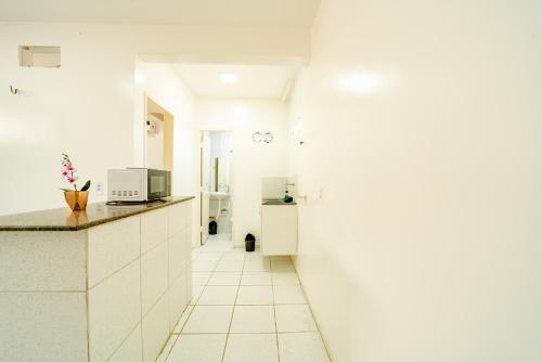 a white kitchen with a counter and a sink at Flat para 2 Pessoas a poucos metros do Aeroporto in Fortaleza