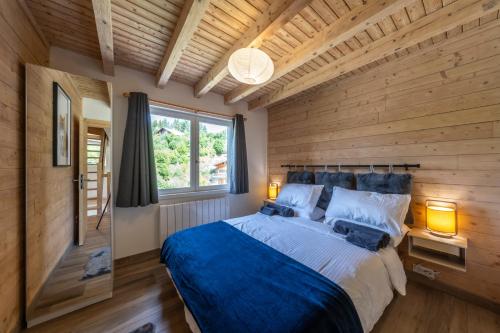a bedroom with wooden walls and a bed with two lamps at Le Bord Du Nant in Arâches-la-Frasse