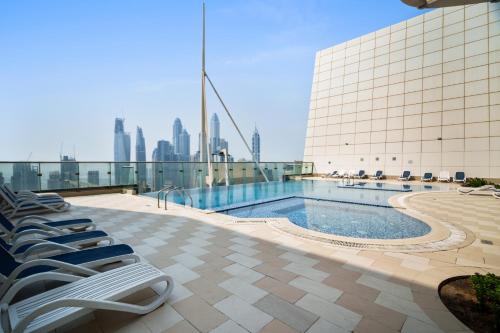 a pool on the roof of a building with chairs at Chic JLT Studio, Lake View, Pool, Metro Access in Dubai