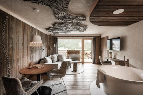 a bathroom with a tub and a living room at Wellnesshotel Der Engel - Tannheimer Tal in Grän