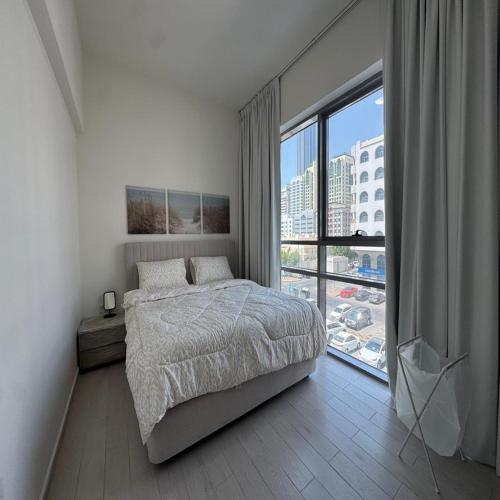 a bedroom with a bed and a large window at Luxury 1-bedroom fully furnished Lifeline apartment in Abu Dhabi
