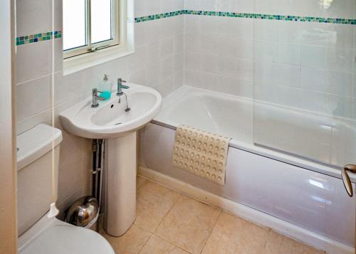 a white bathroom with a sink and a bath tub at Oak Farm Lodges in Roydon