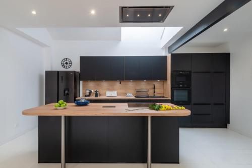 Una cocina con gabinetes negros y una encimera de madera. en La Terrasse - Wifi - Parking - Clim, en Laval