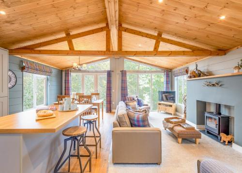 a kitchen and living room with wood ceilings and a table at Thirlestane Woodland Lodges in Lauder