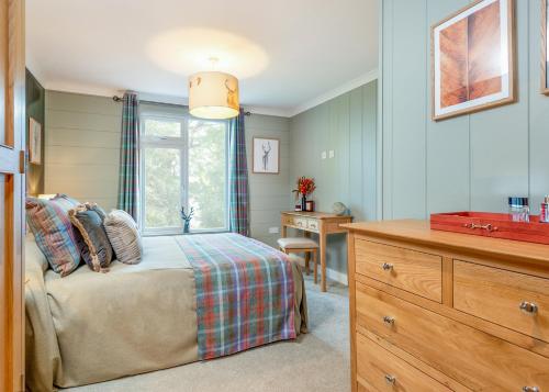 a bedroom with a bed and a dresser and a desk at Thirlestane Woodland Lodges in Lauder