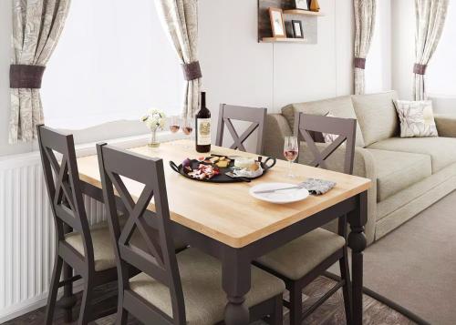 a dining room table with chairs and a couch at Aber Bay Holiday Park in Aberystwyth