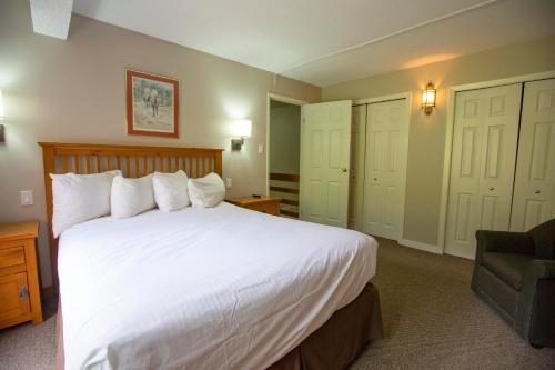 a bedroom with a large white bed and a chair at Panorama Vacation Retreat at Horsethief Lodge in Panorama