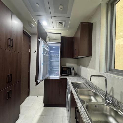 a small kitchen with a sink and a microwave at Premier 2-bedroom Lifeline apartment with free Parking in Abu Dhabi