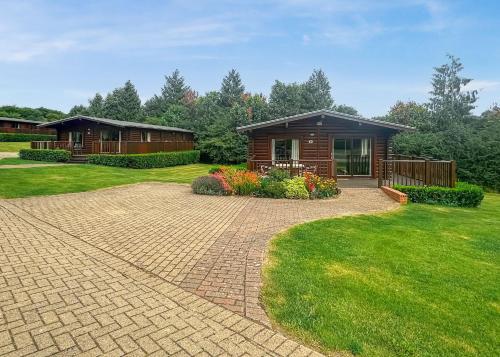 a home with a brick driveway leading to a cabin at Rutland Lodges At Greetham Valley in Greetham