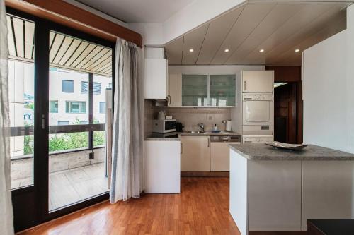 a kitchen with white appliances and a large window at Yamina Luxury Apartment by Quokka 360 - Next to Lido di Lugano in Lugano