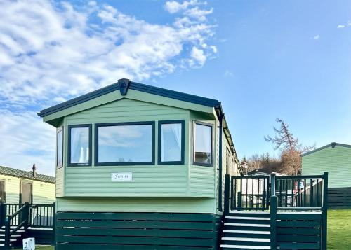 a green tiny house sitting in a yard at Springhouse Country Park in Slaley