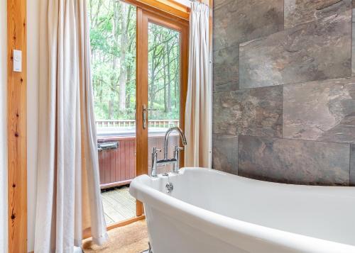 a bath tub in a bathroom with a window at Charlesworth Lodges in Glossop