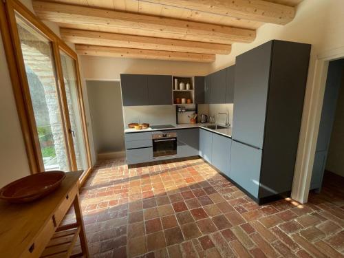 Una cocina con gabinetes grises y piso de ladrillo. en Agriturismo I Giardini di Ron, en Valdobbiadene