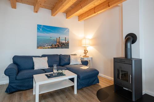 a living room with a blue couch and a stove at Hotel & Ferienunterkünfte Hus Seeblick in Fehmarn