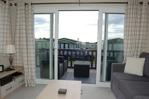 a living room with a couch and a sliding glass door at Premier Caravan 10 at The Vaenol, Tywyn in Tywyn