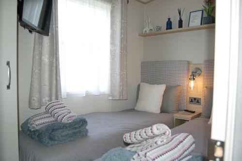 a bedroom with a bed with pillows and a window at Premier Caravan 10 at The Vaenol, Tywyn in Tywyn
