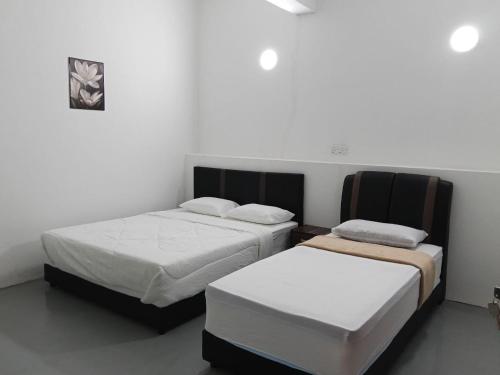 two beds in a room with white walls at KG Hotel in Kampong Sorosob
