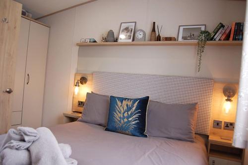a bedroom with a bed with two blue pillows at Premier Caravan 10 at The Vaenol, Tywyn in Tywyn