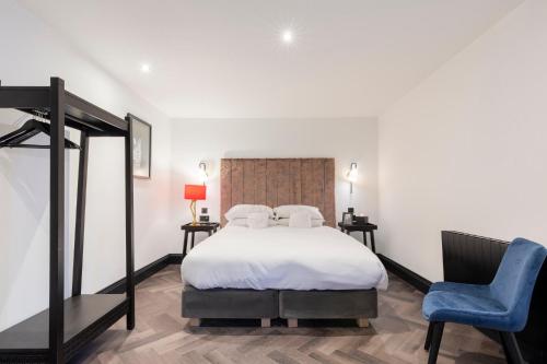 a bedroom with a bed and a blue chair at Wainstones Hotel in Stokesley