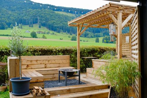 a wooden pergola with a bench and a table at Juralodgespa Détente avec jacuzzi et vue in Courrendlin
