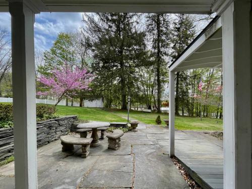 a patio with two benches and a picnic table at Twin Oaks Near Lake Wallenpaupack Historic Home in Hawley