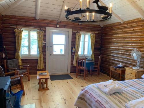 a bedroom with wooden walls and a bed and a chandelier at Au Pic de l'Aurore Motel-Chalets in Perce