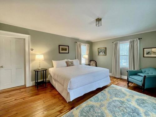a bedroom with a white bed and a blue chair at Twin Oaks Near Lake Wallenpaupack Historic Home in Hawley