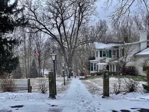 a snow covered street in front of a house at Twin Oaks Near Lake Wallenpaupack Historic Home in Hawley