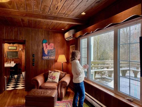 a girl standing in a room looking out of a window at Twin Oaks Near Lake Wallenpaupack Historic Home in Hawley