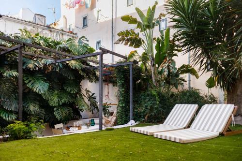two white chairs sitting on the grass in a yard at Pool & Garden Apt In the Heart of Lisbon in Lisbon