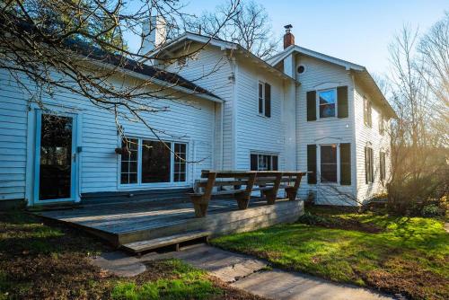 a white house with a wooden deck on the front of it at Twin Oaks Near Lake Wallenpaupack Historic Home in Hawley