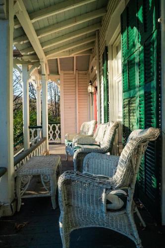 a porch with wicker chairs on a house at Twin Oaks Near Lake Wallenpaupack Historic Home in Hawley