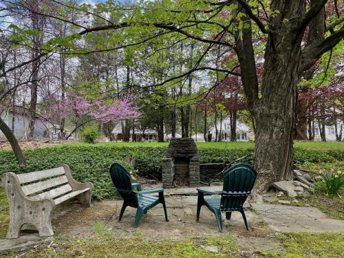 a park with two chairs and a bench and a tree at Twin Oaks Near Lake Wallenpaupack Historic Home in Hawley