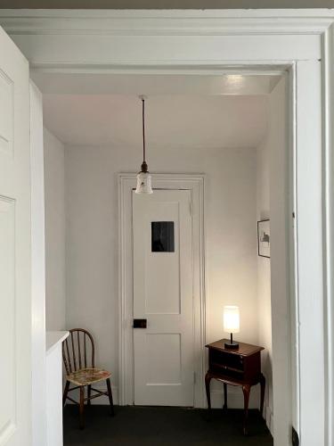 a hallway with a door and a table and a lamp at Twin Oaks Near Lake Wallenpaupack Historic Home in Hawley