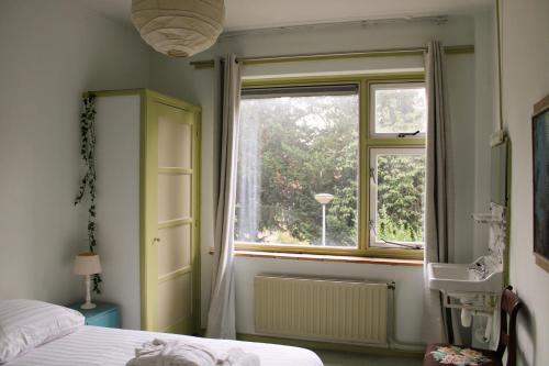 1 dormitorio con ventana, 1 cama y lavamanos en Bie Beno, en Groninga