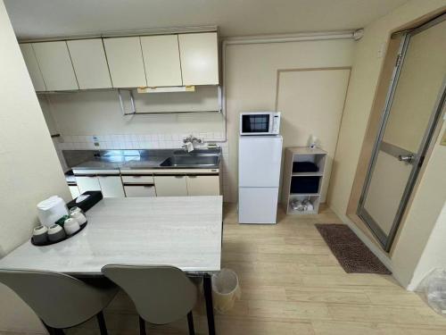 a small kitchen with a table and a white refrigerator at プレストスクエア松島町 in Takamatsu
