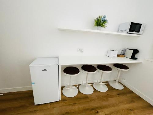 a kitchen with three stools and a counter with a refrigerator at Hostal Ruano in Madrid