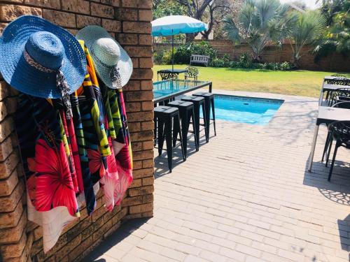 a group of hats hanging on a wall next to a swimming pool at Grafiti Boutique Hotel in Bela-Bela