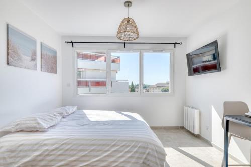 a white bedroom with a bed and a window at L'instant Zen - CNPE Bugey - Centre Meximieux in Meximieux