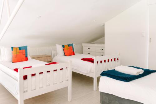 a room with three white beds with colorful pillows at The Salene Hotel & Apartments in Stellenbosch