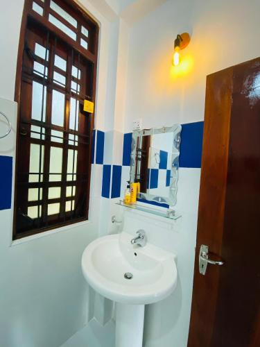 a bathroom with a sink and a mirror and a window at Sudumal Cottage in Ella