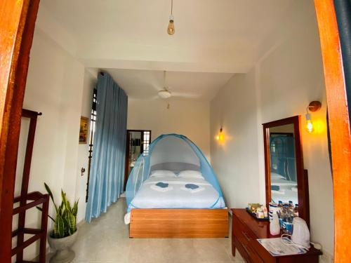 a bedroom with a bed with a blue canopy at Sudumal Cottage in Ella