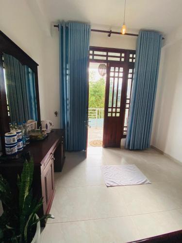 a living room with blue drapes and a door at Sudumal Cottage in Ella