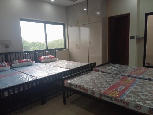 Dos camas sentadas en una habitación con ventana. en Family Guest House Rooms For Rent, en Lahore