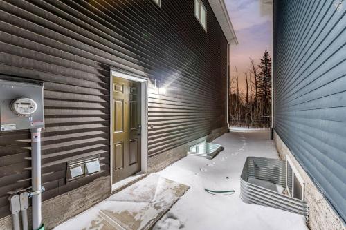 a door on a building with a bench in the snow at New Builtspacious Suite Bsmtgamesnetflix in Edmonton