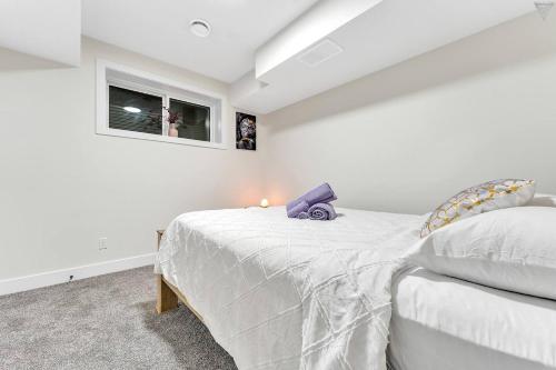 a white bedroom with a bed and a window at New Builtspacious Suite Bsmtgamesnetflix in Edmonton