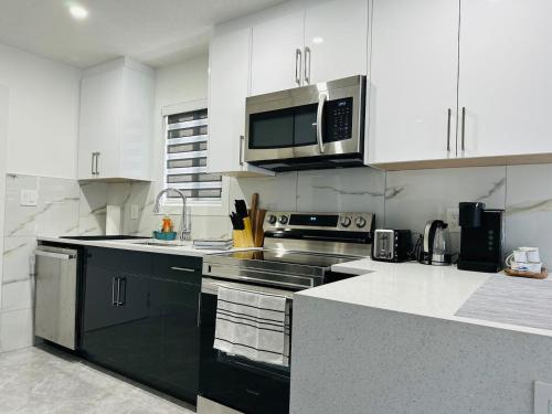 una cucina con elettrodomestici in acciaio inossidabile e armadietti bianchi di Cozy 2 Bedroom Suite Pet Friendly Garage a Edmonton